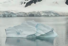 Small iceberg with snow covered mountains in the background