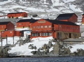 Brightly painted red buildings on a snowy shore.